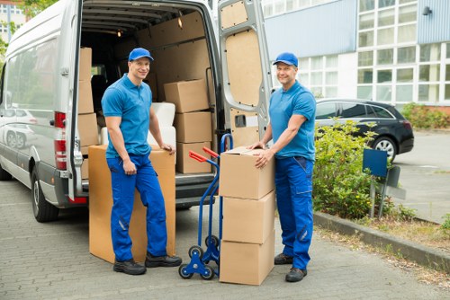Local movers carrying packed boxes through a residential property in Hatton