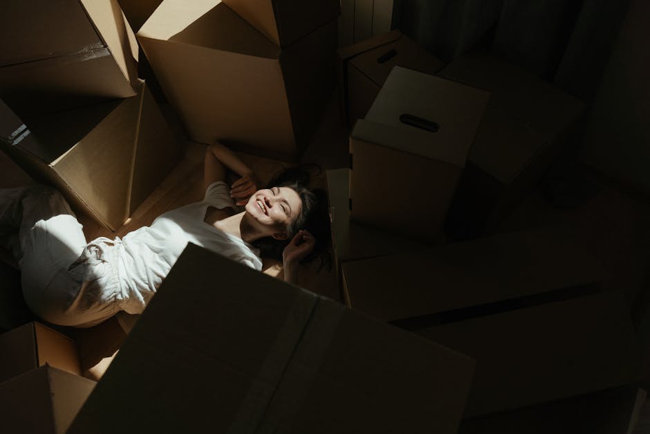 Inside a well-lit bedroom with natural light coming through an open window, a man and a young woman are engaged in home relocation activities as part of a furniture transport or packing and moving pro